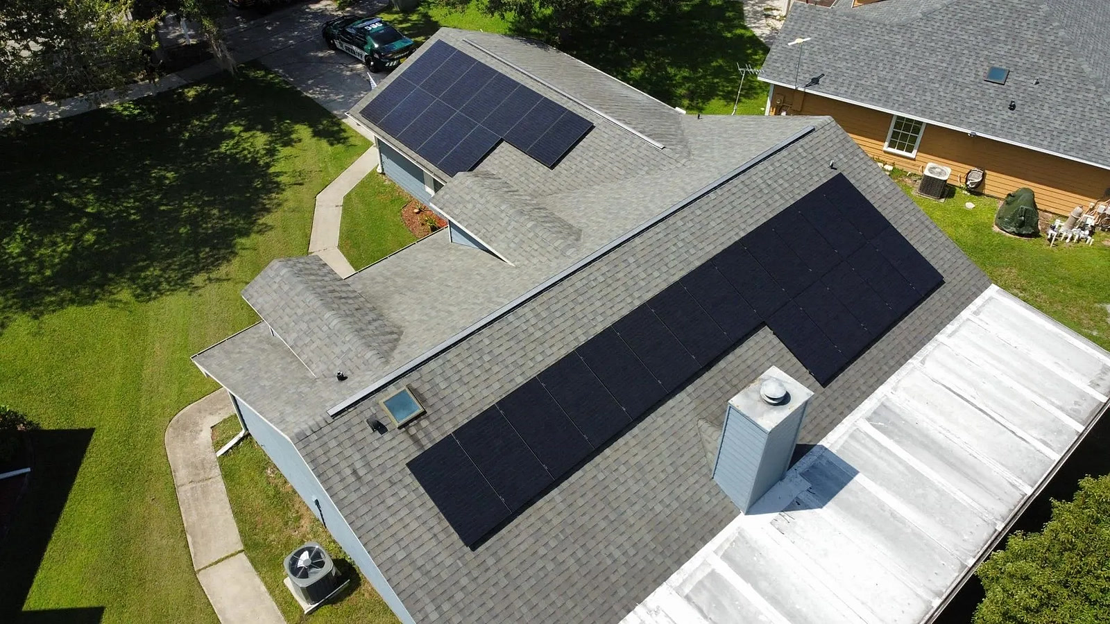 Aerial view of a solar array along the roof ridge under a clear blue sky