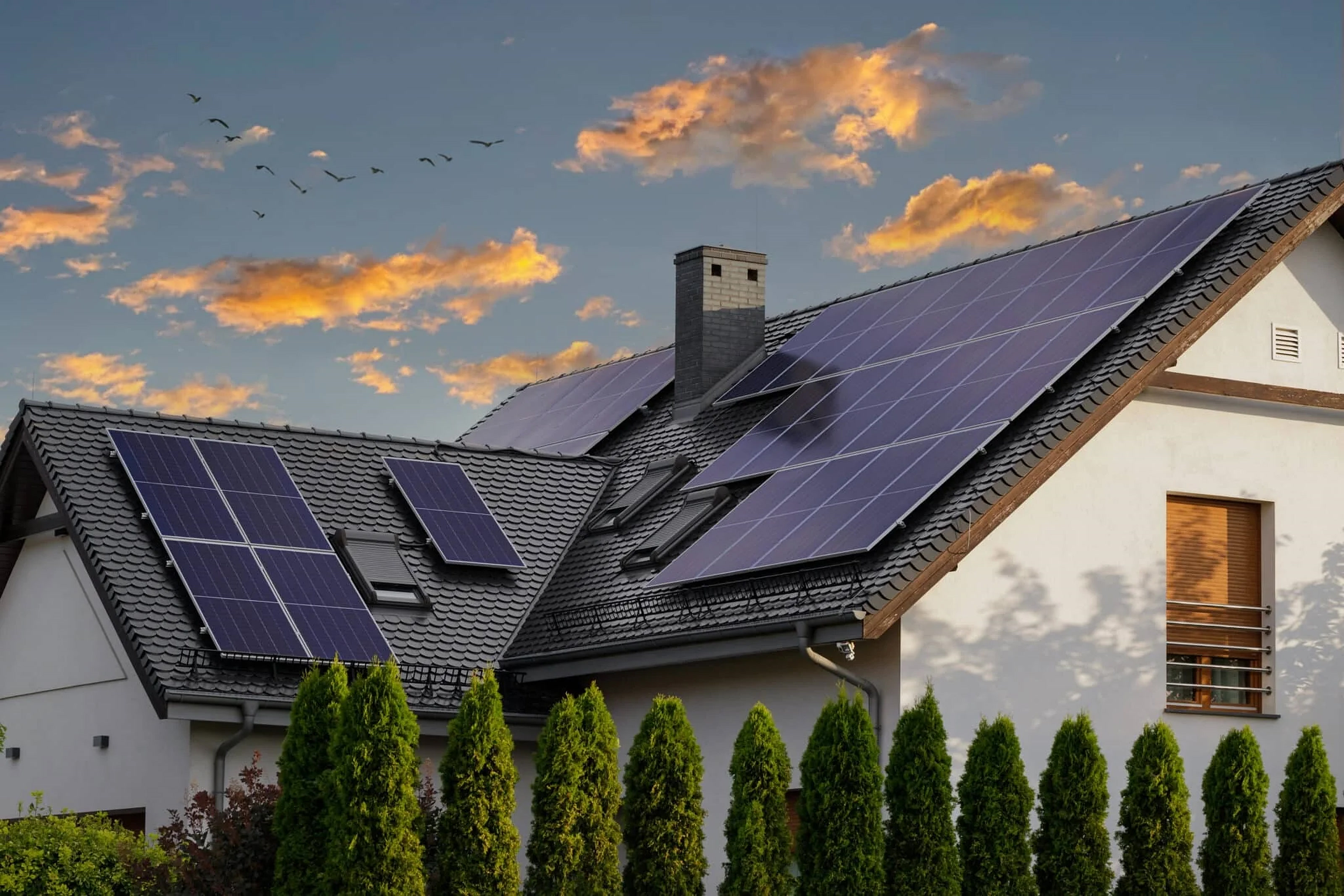Solar panels installed on a tile roof under a dramatic dusk sky