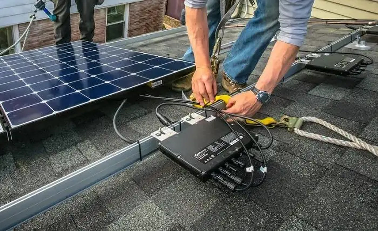Microinverter being wired to a solar panel on a roof