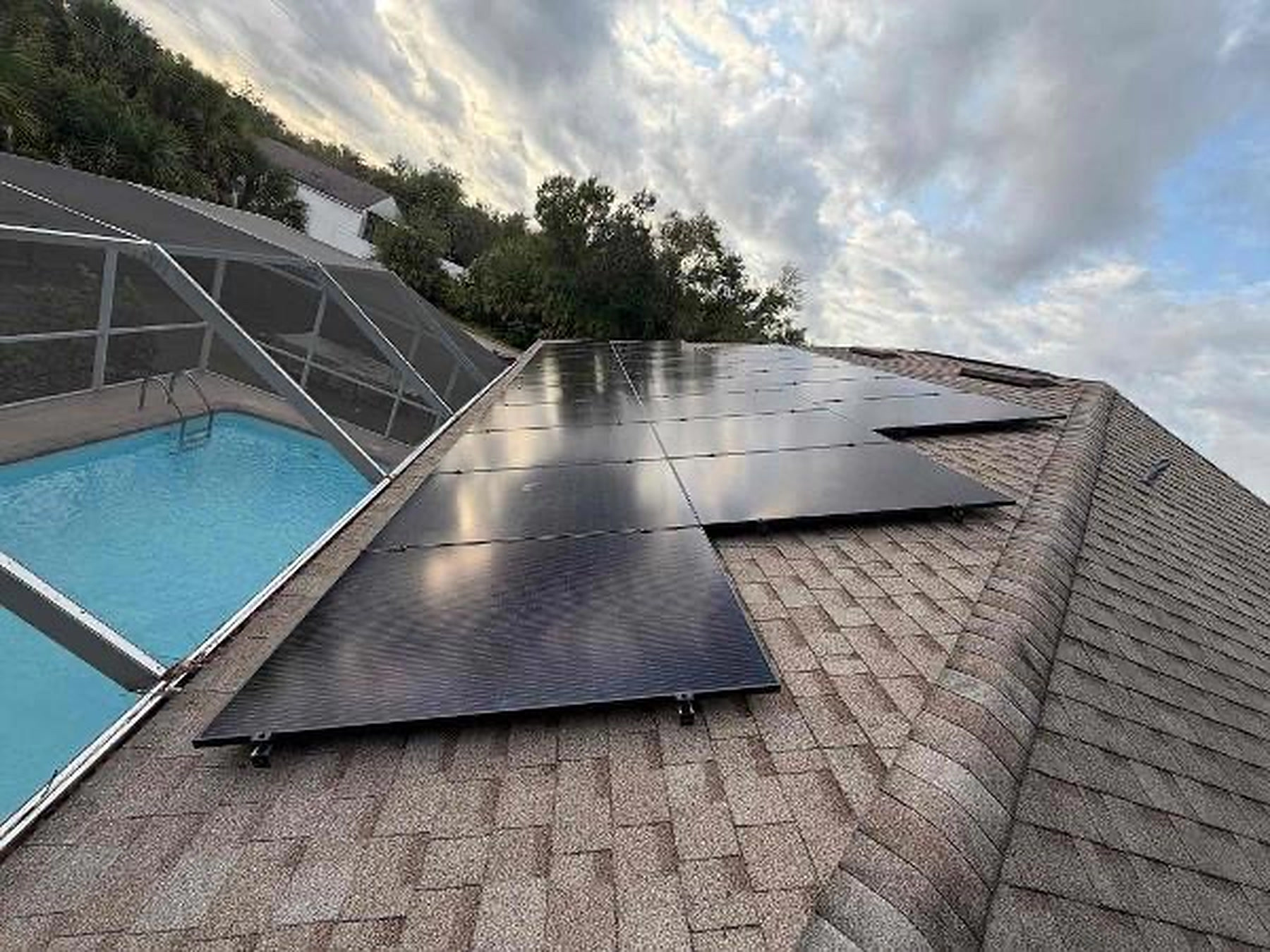 Solar array installed on a roof overlooking a screened pool enclosure